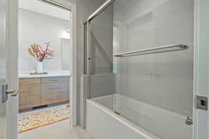 Full bathroom with visible vents, vanity, tile patterned flooring, and shower / bath combination with glass door