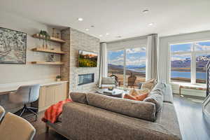 Living room with built in study area, recessed lighting, dark wood-type flooring, and a fireplace