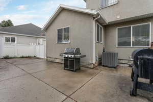 View of patio featuring central air condition unit, a grill, and fence