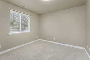 Carpeted spare room with baseboards and visible vents