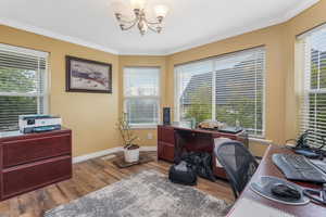 Office area with baseboards, wood finished floors, an inviting chandelier, and crown molding