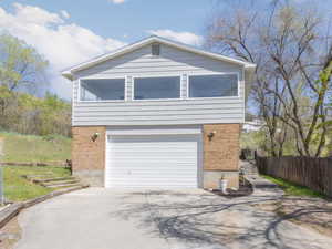 View of home's exterior with an attached garage, fence, brick siding, and concrete driveway