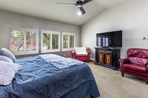 Bedroom with vaulted ceiling, carpet, a ceiling fan, and multiple windows