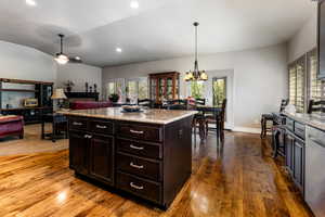 Kitchen with plenty of natural light, vaulted ceiling, pendant lighting, and dark wood-style flooring