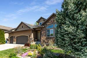 Craftsman inspired home with stone siding, driveway, stucco siding, and a garage