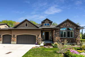 Craftsman inspired home with concrete driveway, stone siding, an attached garage, a front yard, and stucco siding