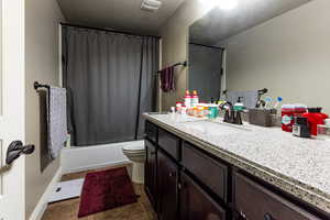 Full bathroom featuring shower / bath combo, visible vents, toilet, and vanity
