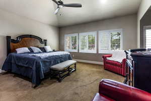 Carpeted bedroom with vaulted ceiling, a ceiling fan, and baseboards