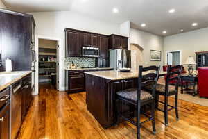 Kitchen featuring a center island, a breakfast bar area, arched walkways, stainless steel appliances, and dark wood-style flooring
