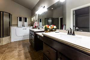 Bathroom with a stall shower, a garden tub, high vaulted ceiling, and washer / dryer