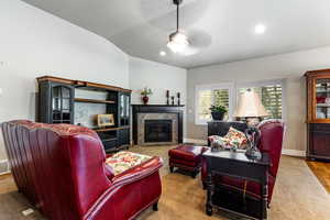 Carpeted living area featuring vaulted ceiling, baseboards, recessed lighting, ceiling fan, and a tile fireplace
