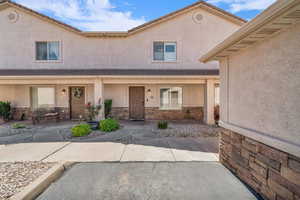 Property entrance featuring stone siding, covered porch, and stucco siding