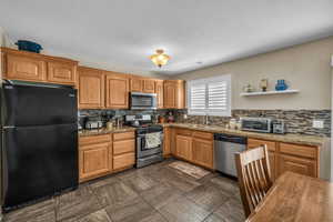 Kitchen featuring appliances with stainless steel finishes, tasteful backsplash, open shelves, and brown cabinetry