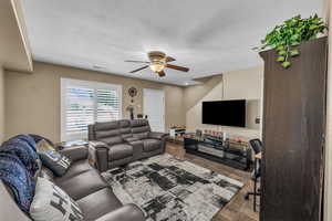 Living room featuring a desk, a ceiling fan, a textured ceiling, and wood finished floors