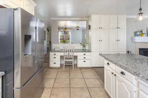 Kitchen with stainless steel fridge with ice dispenser, white cabinetry, light tile patterned floors, decorative light fixtures, and a notable chandelier