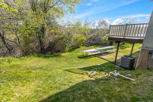 View of yard featuring central AC and a deck