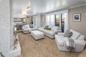 Carpeted living room featuring a notable chandelier and ornamental molding