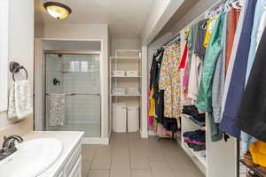 Bathroom featuring a shower stall, vanity, tile patterned floors, and a spacious closet