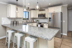 Kitchen featuring a peninsula, ornamental molding, a sink, and appliances with stainless steel finishes