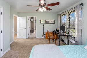 Bedroom with carpet flooring, baseboards, a ceiling fan, and connected bathroom