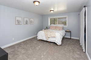 Carpeted bedroom featuring baseboards and a textured ceiling