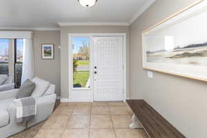 Entryway with light tile patterned floors, baseboards, and ornamental molding