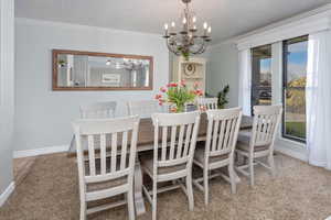 Dining space with baseboards, an inviting chandelier, and ornamental molding