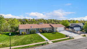 Ranch-style home with a chimney, stucco siding, an attached garage, driveway, and a front yard