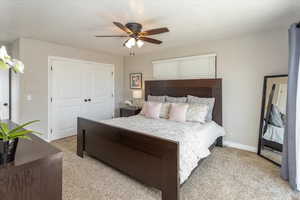 Bedroom with ceiling fan, baseboards, a closet, and light colored carpet