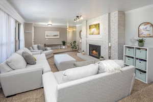 Living room with ornamental molding, carpet flooring, and a brick fireplace
