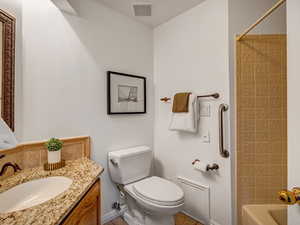 Main level full bath featuring toilet, shower / bathing tub combination, and vanity.