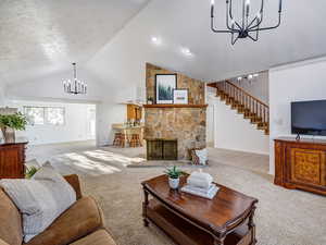 Front living room with vaulted ceiling, fireplace, double chandeliers, and stairs