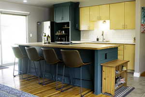 Kitchen with refrigerator, tasteful backsplash, butcher block countertops, and a sink