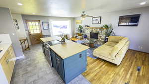 Kitchen with electric stove, blue cabinetry, ceiling fan, and recessed lighting