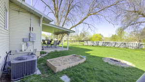 View of yard featuring cooling unit, a fenced backyard, a patio, and a fire pit
