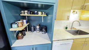 Kitchen featuring open shelves, a sink, dishwasher, light countertops, and backsplash