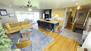 Living room featuring light wood flooring, a ceiling fan, and recessed lighting