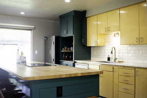 Kitchen with refrigerator, black electric cooktop, wooden counters, and a sink