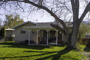 Back of property with fence, a shingled roof, a yard, and a patio