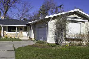 View of property with a chimney, a yard, an attached garage, driveway, and a porch
