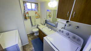 Clothes washing area with a sink, stone tile floors, baseboards, hookup for a washing machine, and laundry area