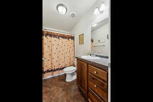 Bathroom featuring vaulted ceiling, vanity, a shower with curtain, toilet, and tile patterned flooring