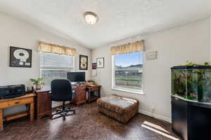 Office area with dark tile patterned floors, baseboards, a textured ceiling, and a healthy amount of sunlight