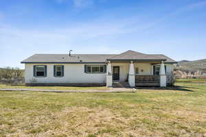 View of front facade with fence, a front lawn, covered porch, and roof with shingles
