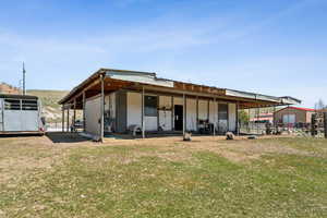 Back of house featuring an outdoor structure and a yard