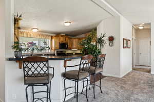 Kitchen featuring stainless steel appliances, a breakfast bar, baseboards, and carpet