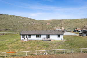 Rear view of property featuring a fenced backyard, a deck with mountain view, and a yard