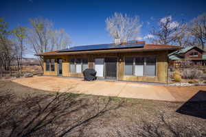 Back of property featuring solar panels, a patio area, and metal roof