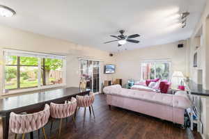 Living area featuring dark wood finished floors, a healthy amount of sunlight, and ceiling fan
