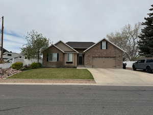 View of front of house with a garage, driveway, a front lawn, and fence